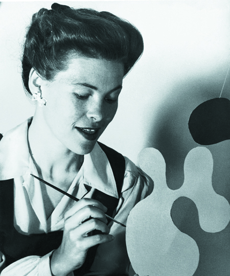 A profile view of Ray Eames painting an Eames Plywood Mobile